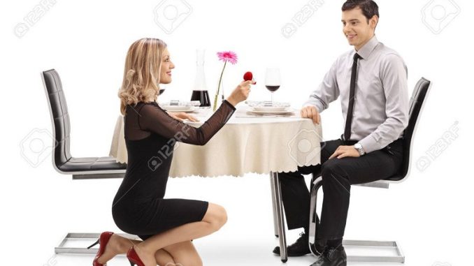 Young woman kneeling and proposing to her boyfriend